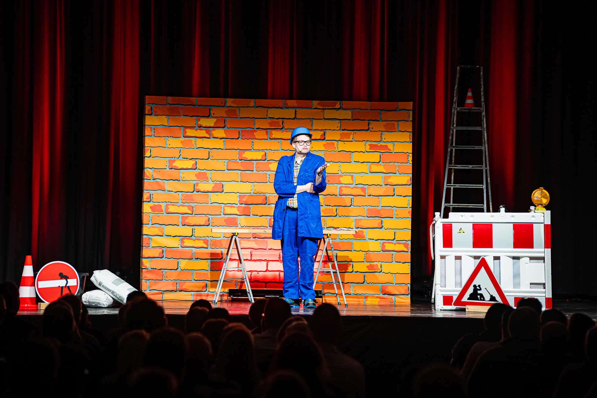 Handwerker Peters mit Live-Comedy vor orangener Mauer
