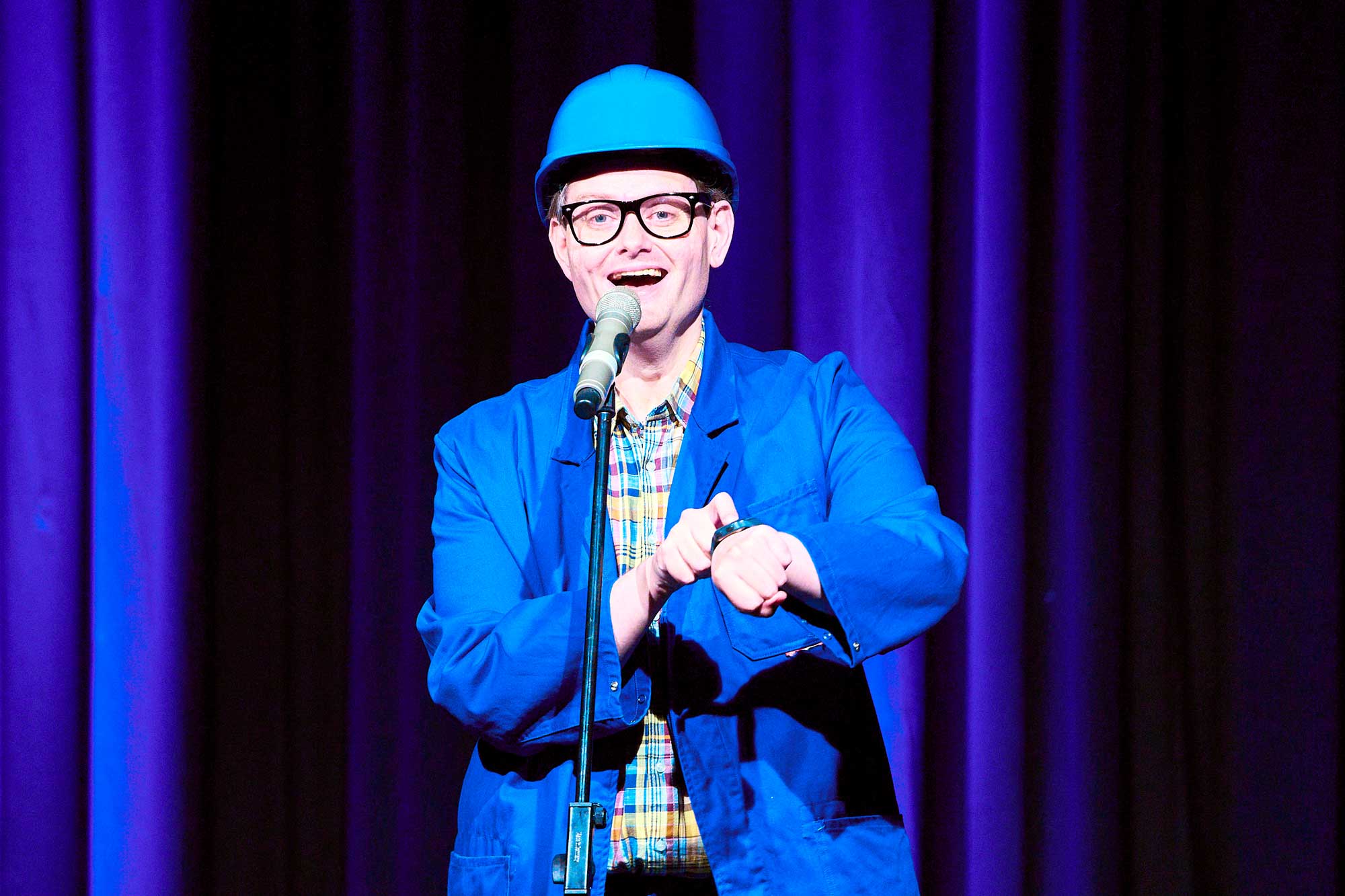 Handwerker Peters live mit Stand-up und zeigt auf Armband-Uhr