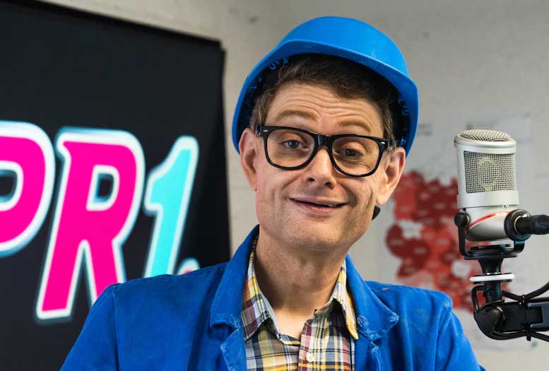 Handwerker Peters im Studio vor dem Mikrofon im Hintergrund das RPR1-Logo